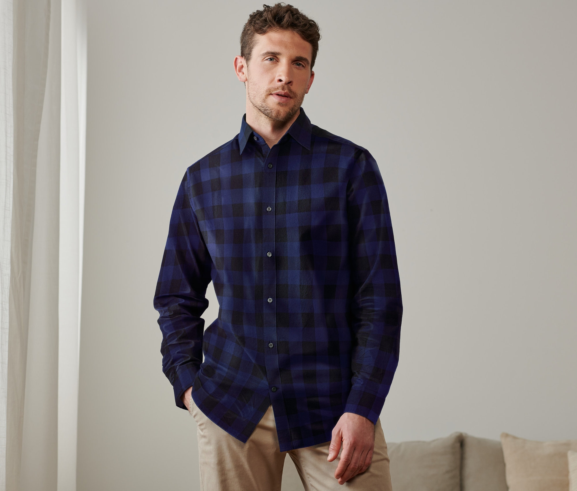 Mężczyzna pozuje w niebieskiej koszuli flanelowej w kratę.