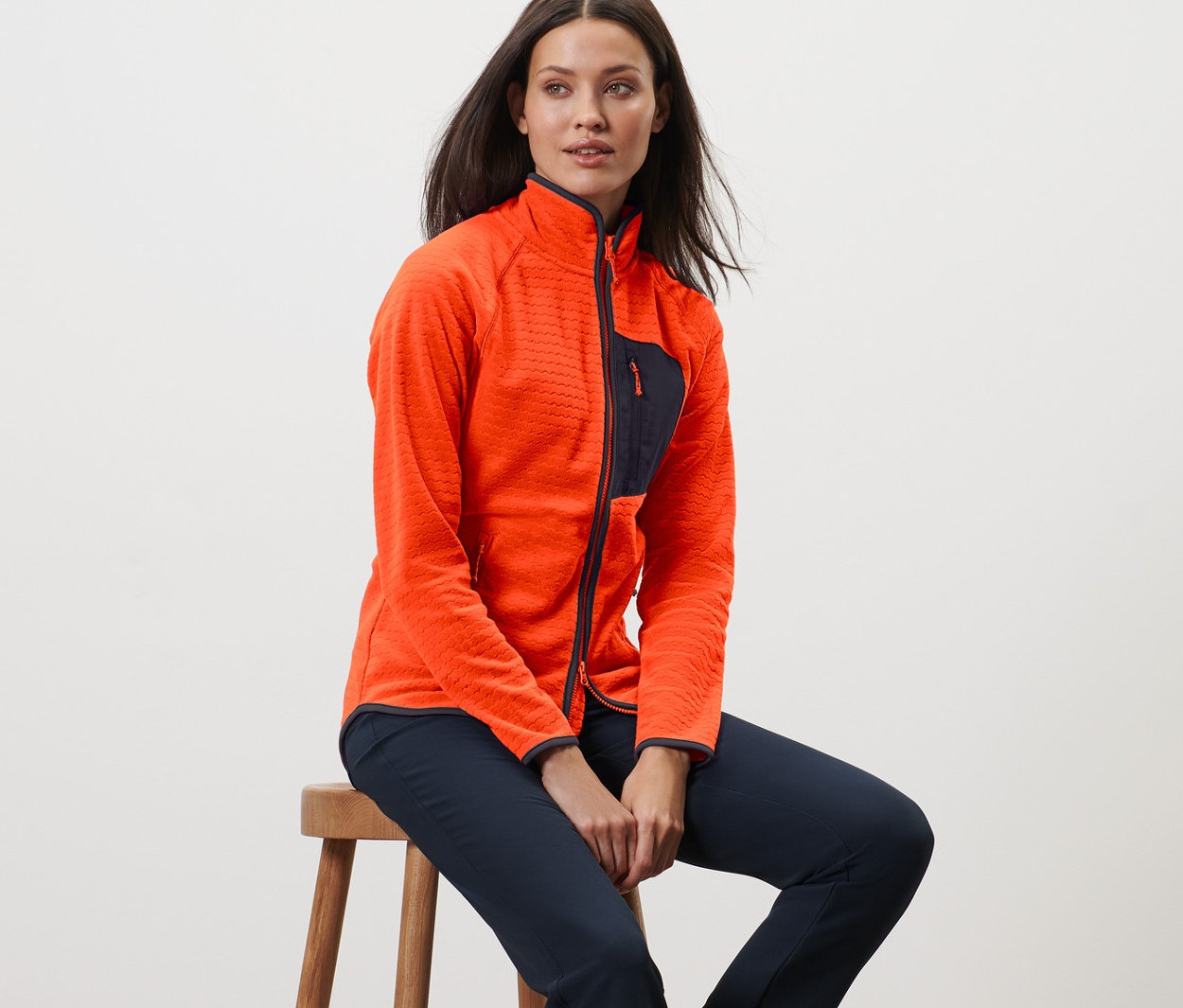 Kobieta siedzi na stołku i ma na sobie bluzę z polaru.