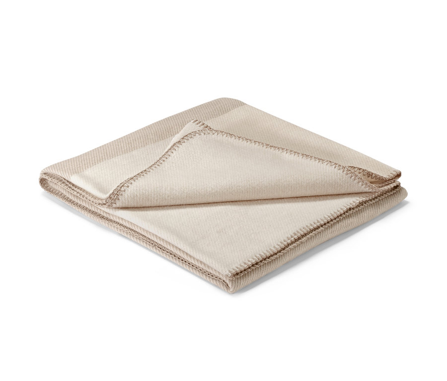 Beżowa narzuta z ozdobnym obszyciem.