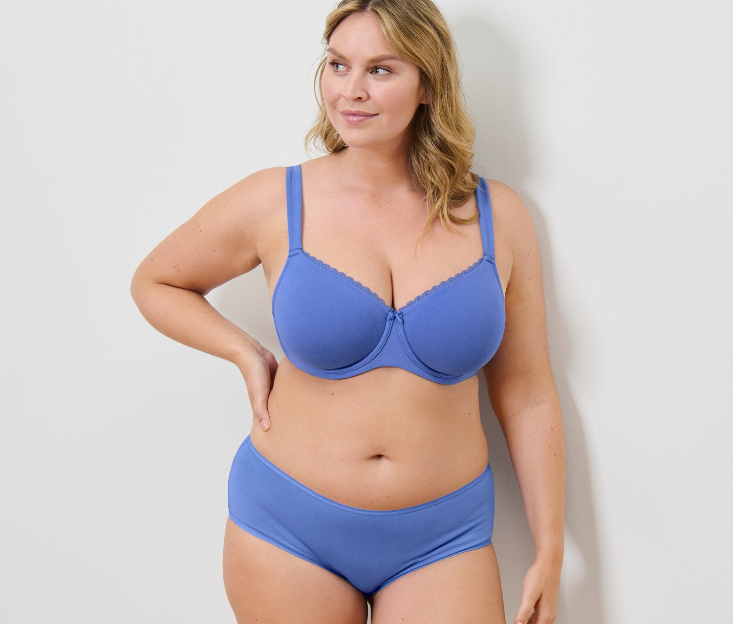 Kobieta pozuje w niebieskim biustonoszu z fiszbinami i majtkach.