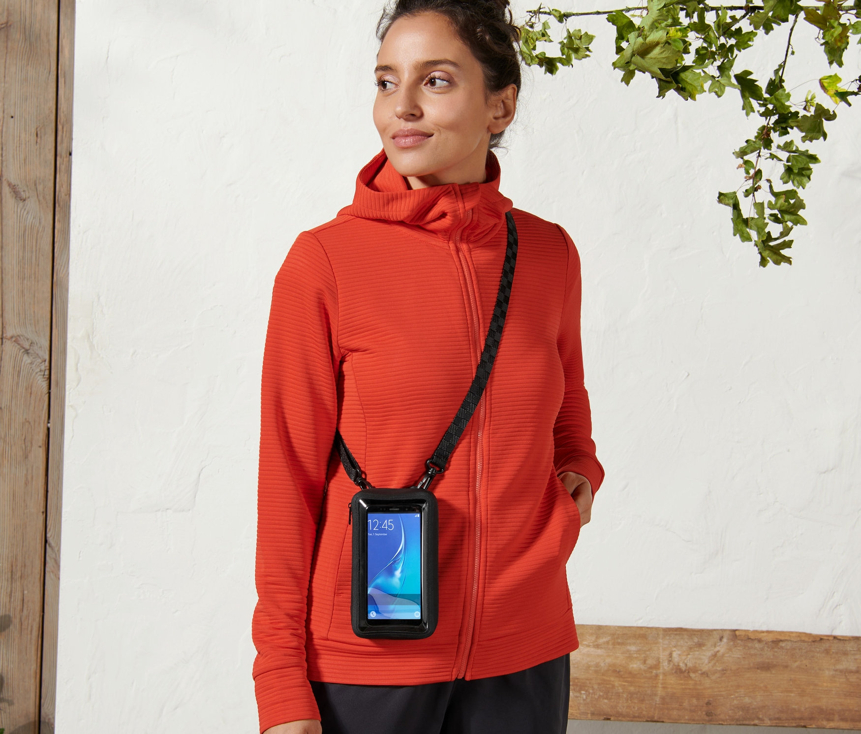 Kobieta nosi torbę na smartfon 2 w 1 z czarnym paskiem na ciele.