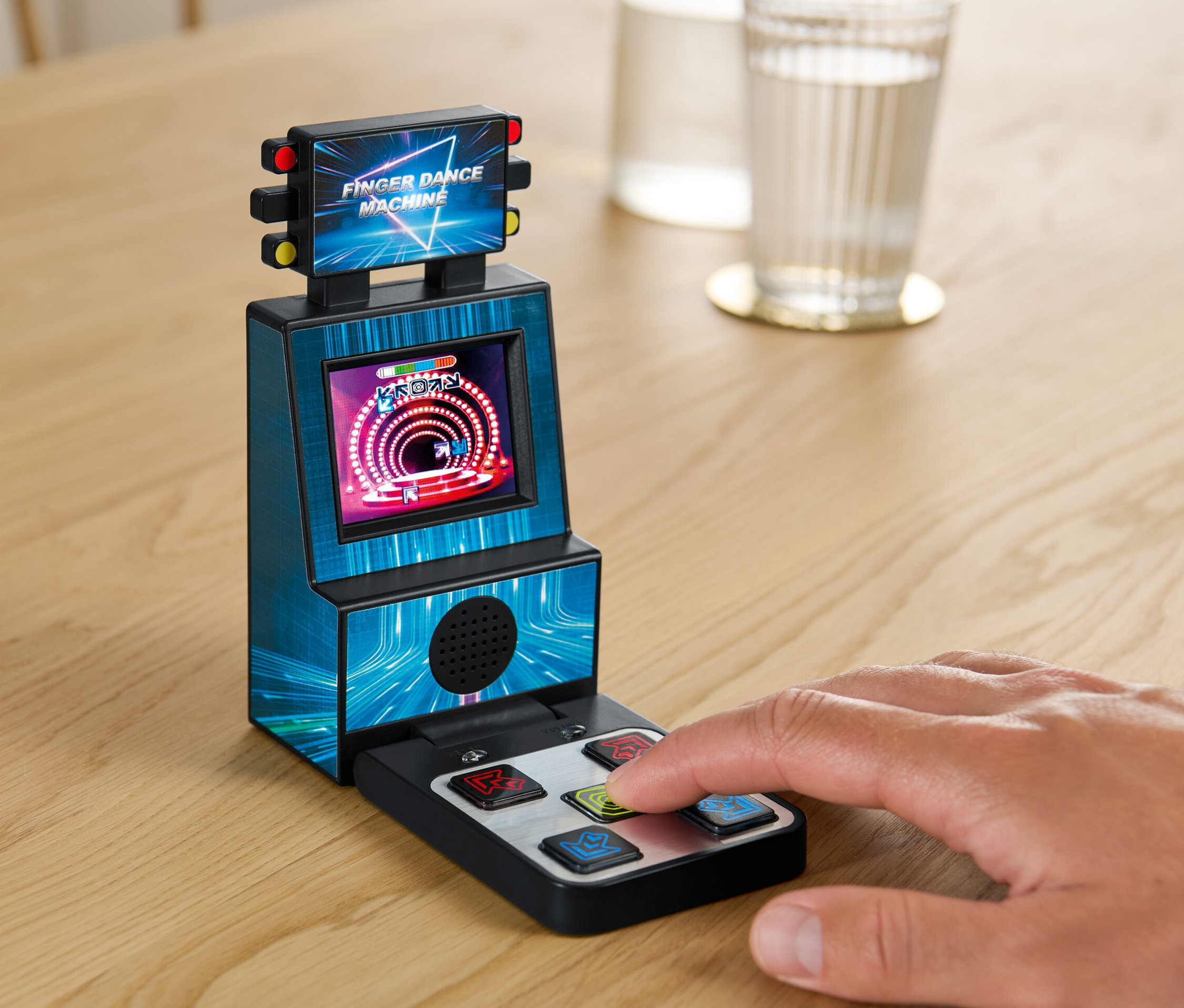 Ręka gra na Automacie do tańca palcami na stole obok szklanki wody.