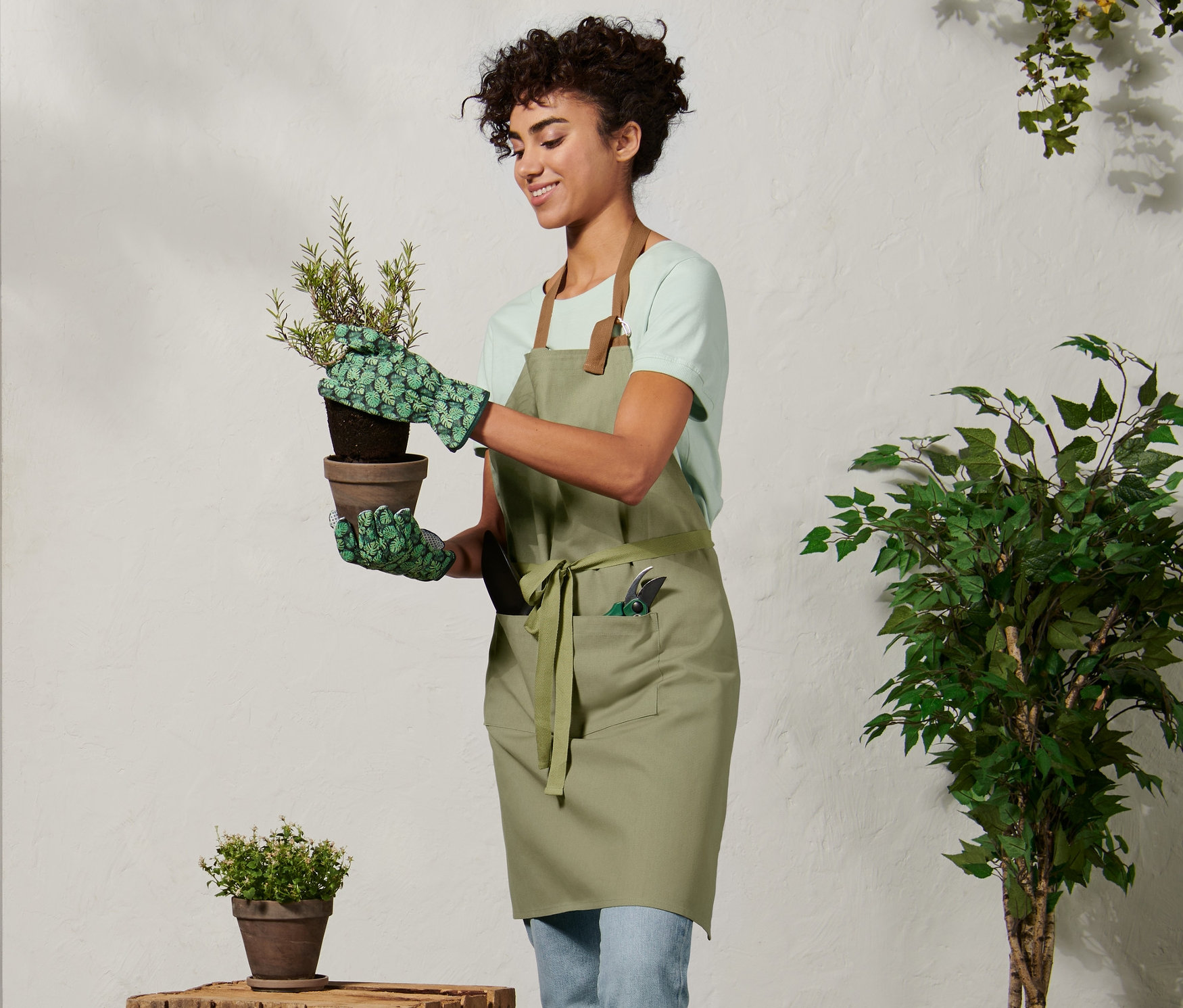 Kobieta w fartuchu ogrodniczym trzyma doniczkę.