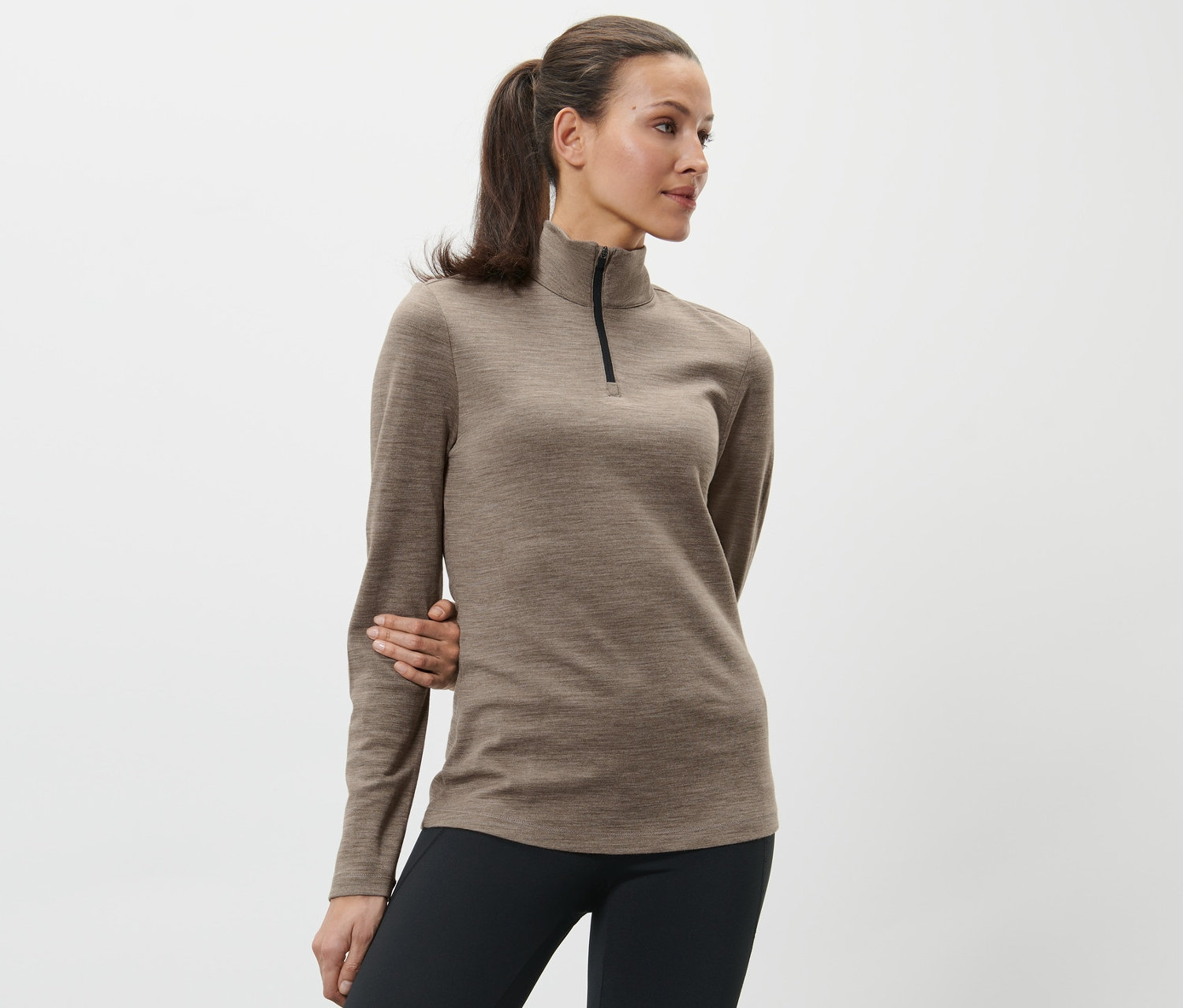 Kobieta pozuje w brązowej koszulce z wełną z certyfikatem RWS i czarnych legginsach.