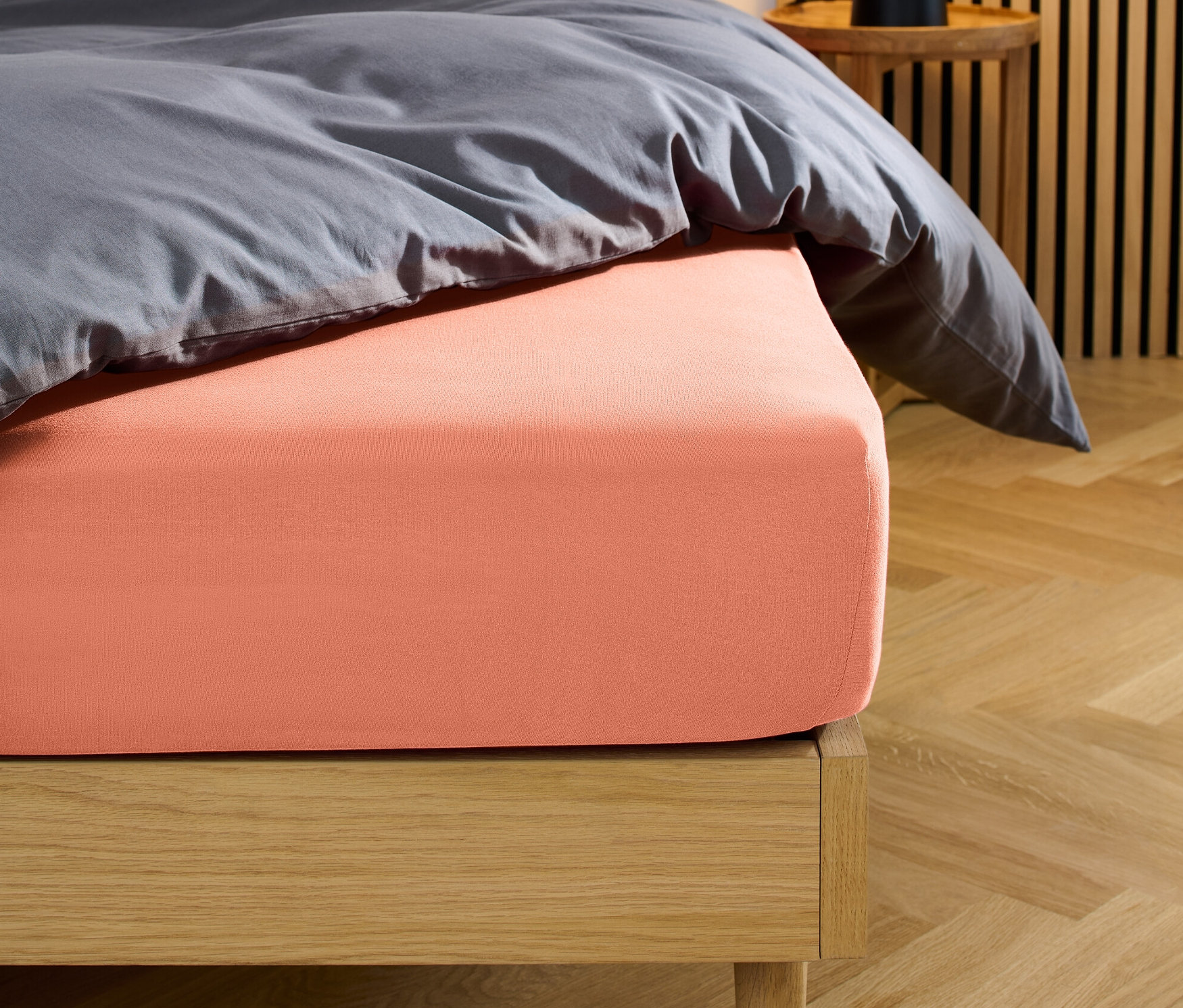 Łóżko z koralowym prześcieradłem dżersejowym z gumką.