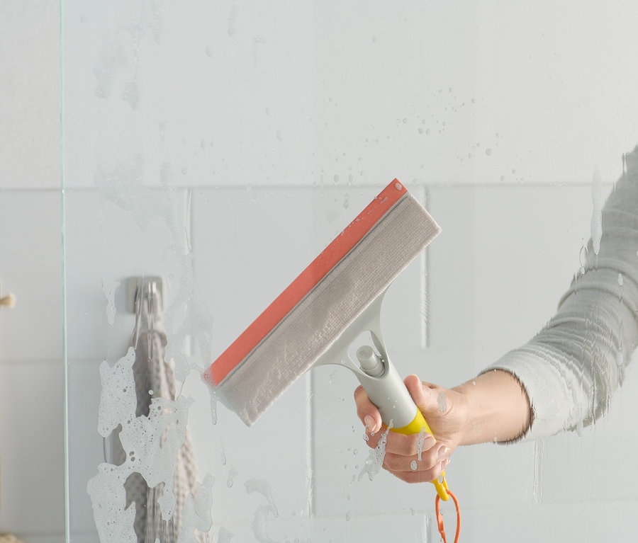 Kobieta używa myjki do szyb 3 w 1 na szklanym ekranie prysznicowym.