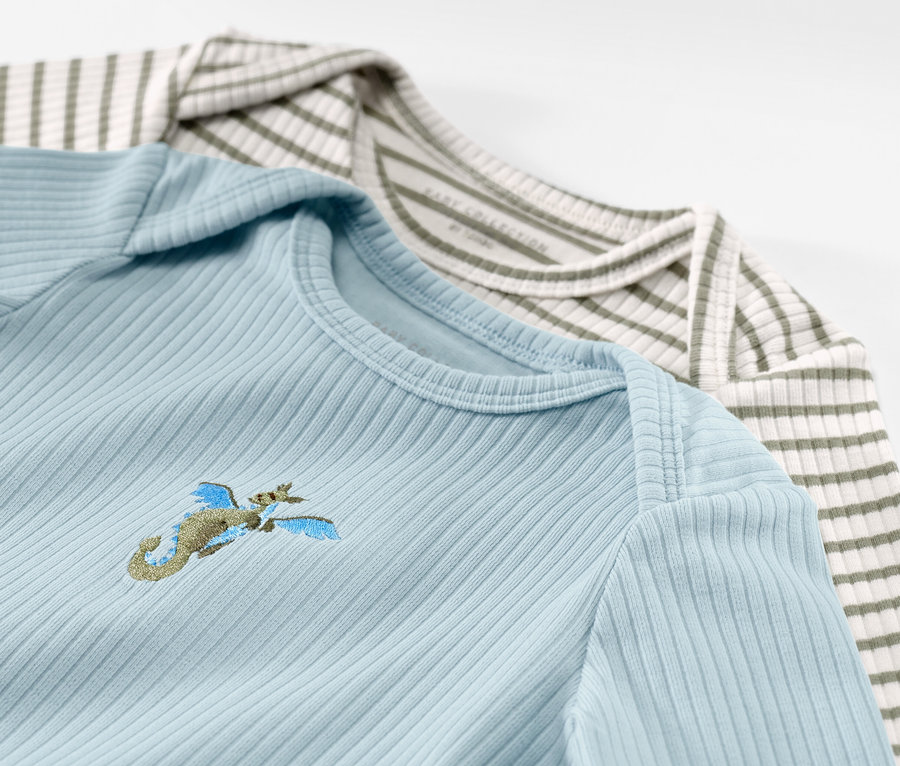 Dwie koszulki niemowlęce z długim rękawem o prążkowanej fakturze, błękitna z haftem i zielono-biała w paski.