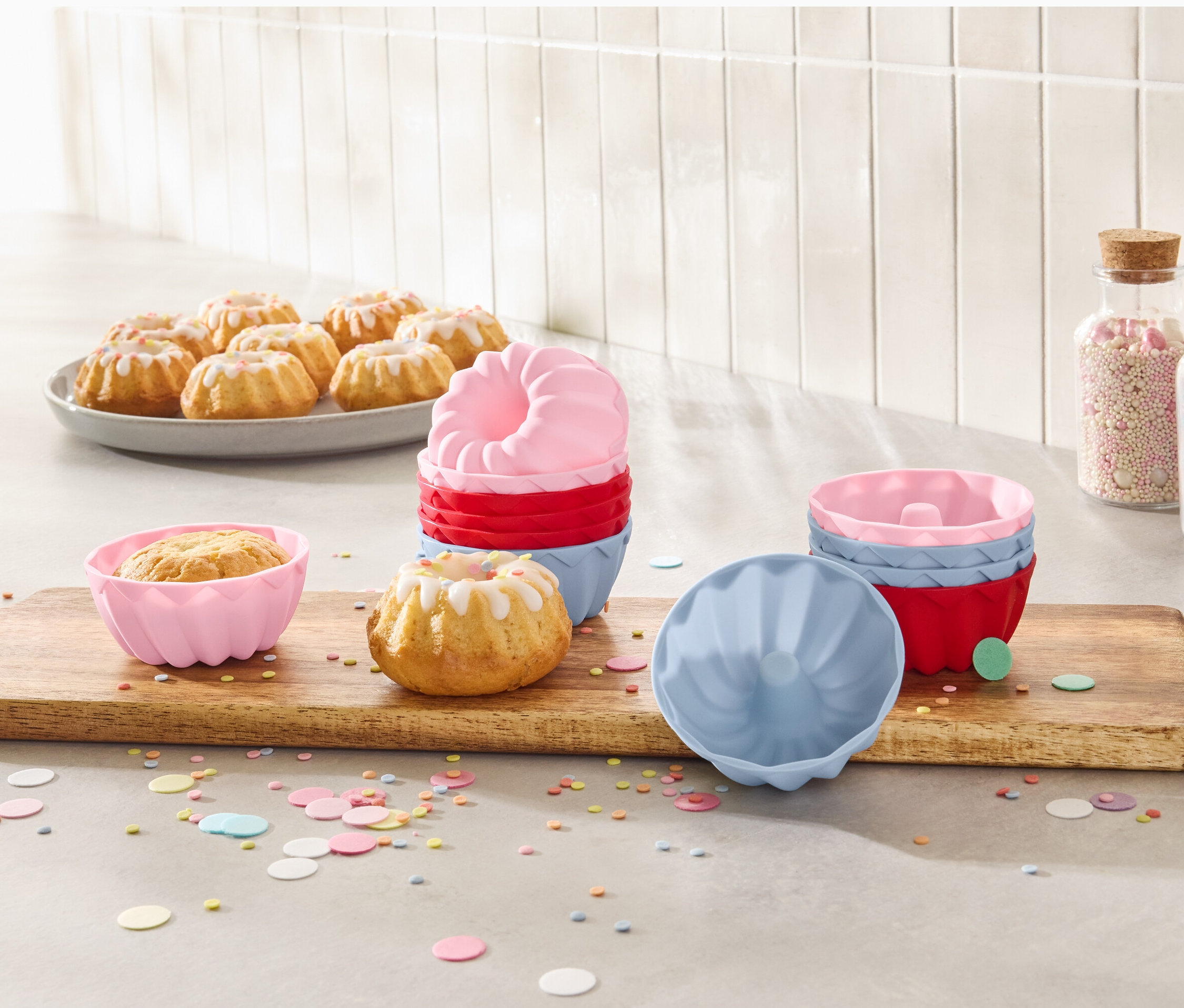 Minibabeczki na talerzu i foremki do minibabek, 12 sztuk, na drewnianej desce.