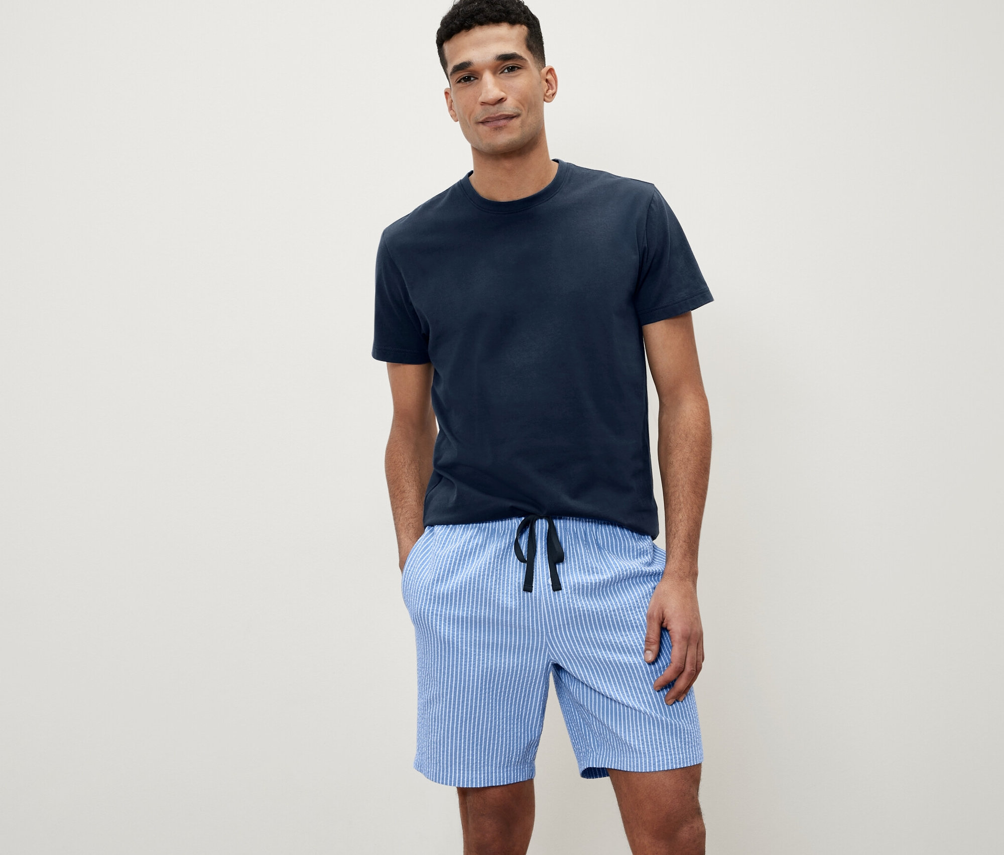 Mężczyzna pozuje w piżamie z krótkimi spodenkami z tkaniny.