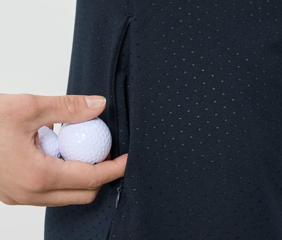 Ręka wkłada piłki golfowe do kieszeni sukienki sportowej.