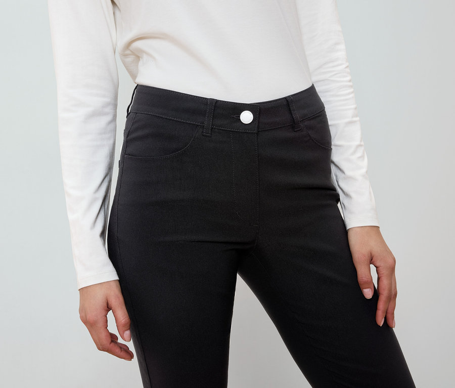 Kobieta ma na sobie czarne spodnie i białą koszulę.