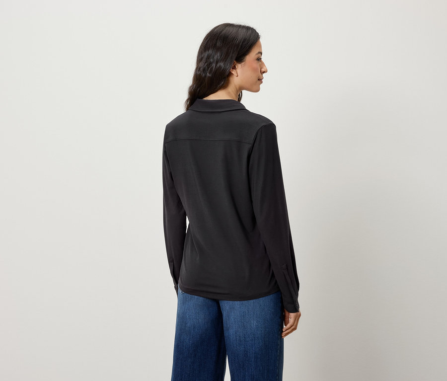 Widok z tyłu kobiety z długimi włosami w czarnej koszuli z długim rękawem i niebieskich dżinsach.