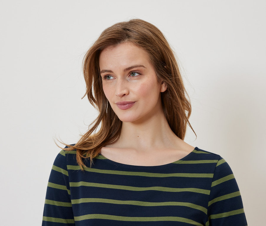 Portret kobiety z brązowymi włosami w bluzce w paski koloru granatowo-zielonego.