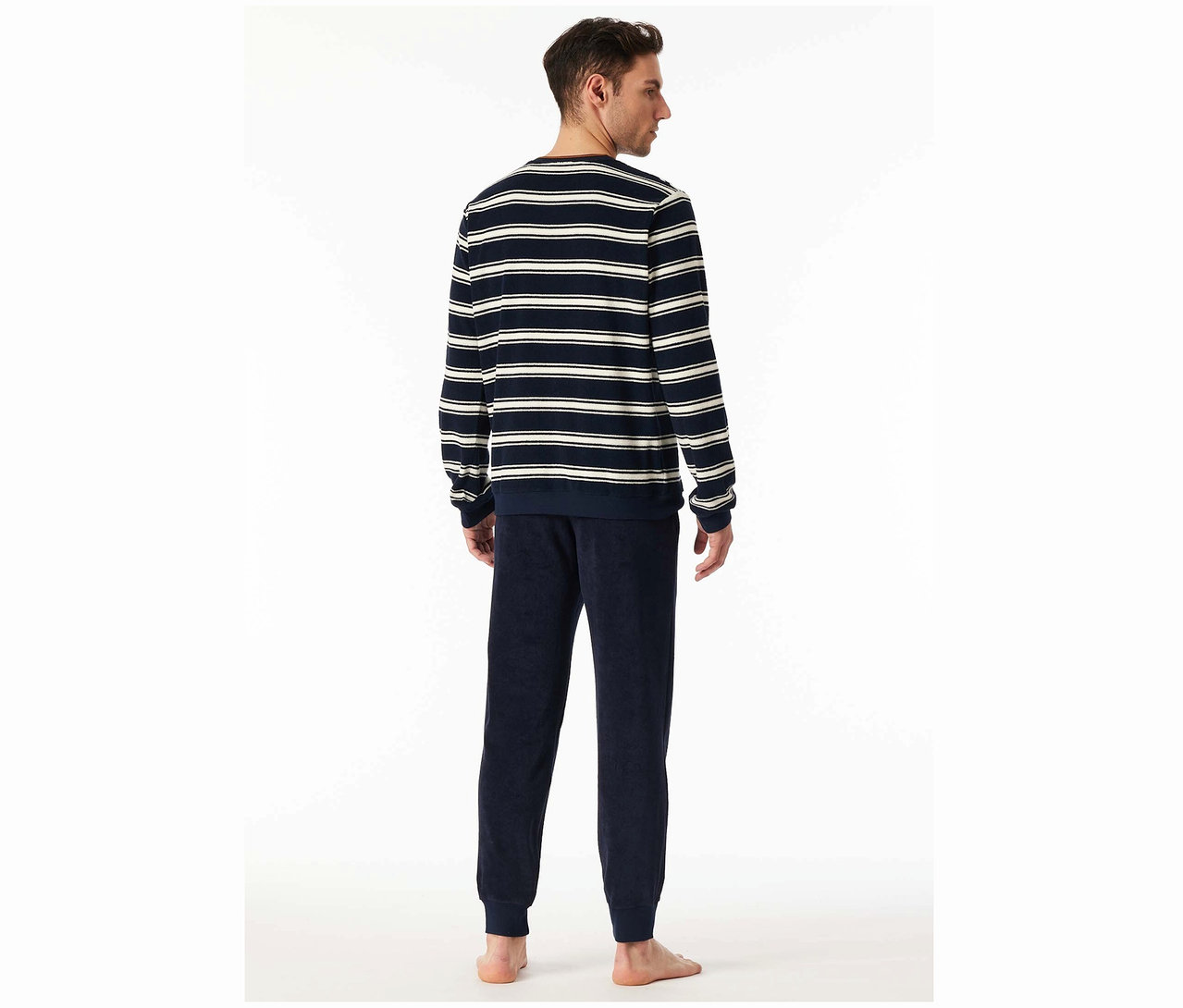 Mężczyzna tyłem do kamery ma na sobie top w paski i granatowe spodnie.