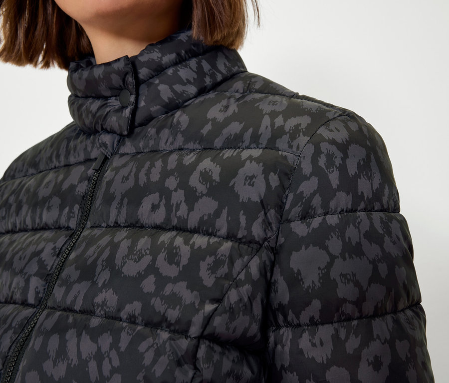 Górna część kobiety w czarnej pikowanej kurtce ze zwierzęcym nadrukiem.