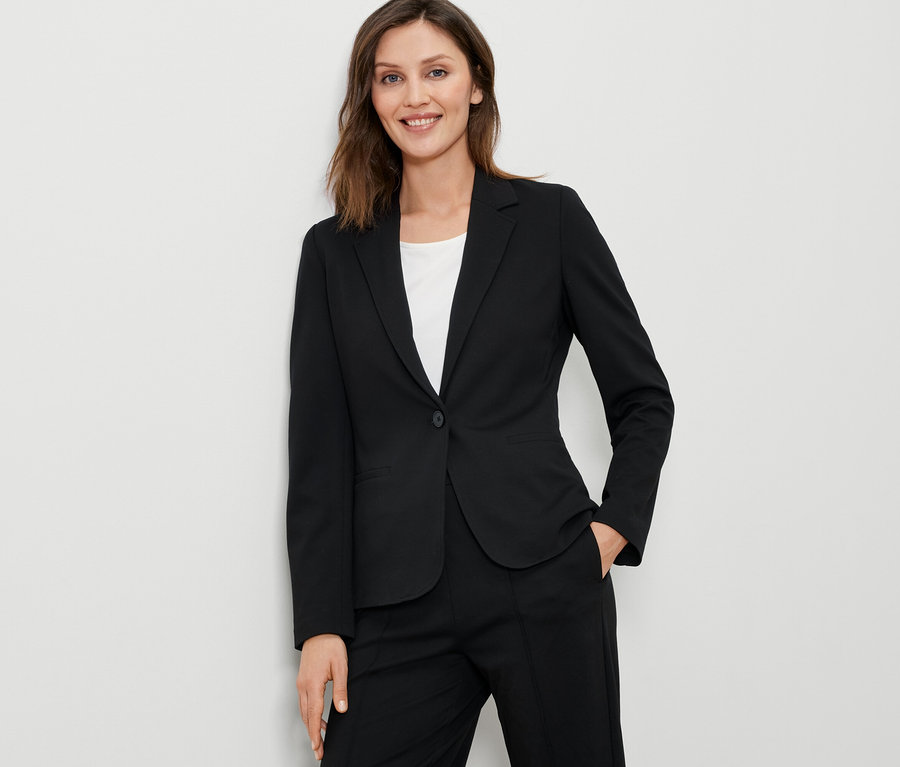 Kobieta ma na sobie czarny żakiet z dżerseju.