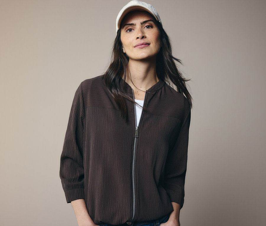 Kobieta w brązowej kurtce i białej czapce z daszkiem.