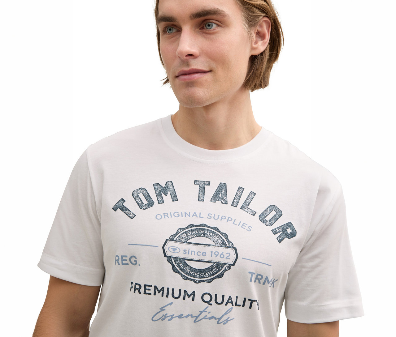 Mężczyzna ma na sobie białą koszulkę z logo Tom Tailor.