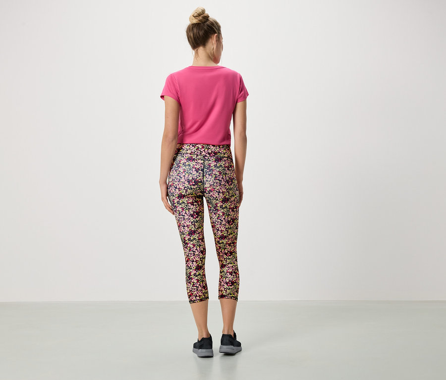 Tył kobiety w różowej koszulce i kwiecistych legginsach.