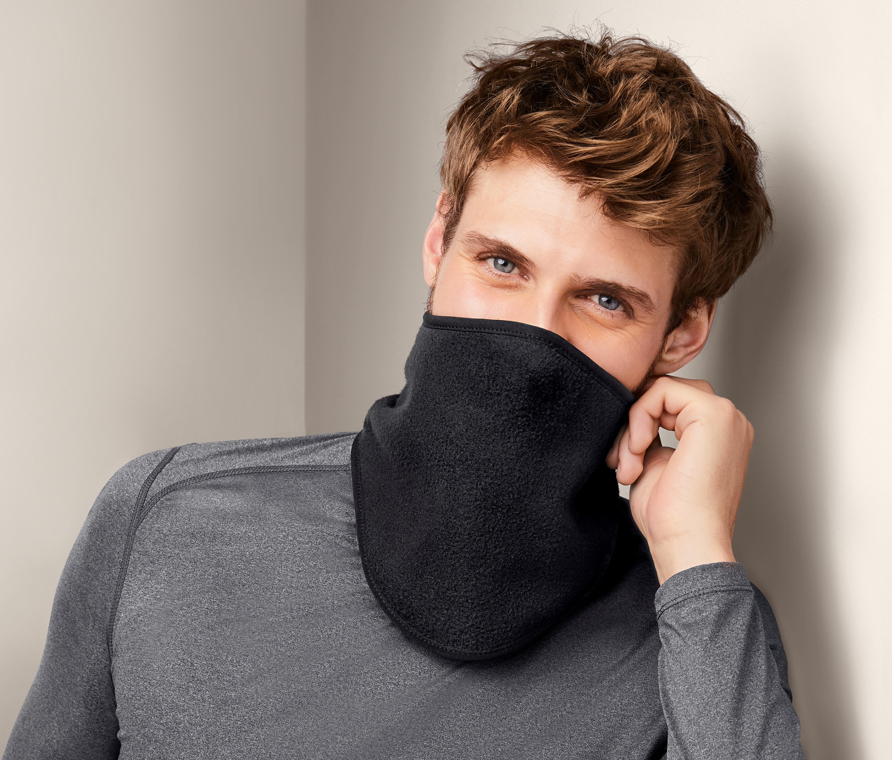 Mężczyzna o brązowych włosach i niebieskich oczach ma na sobie czarny kołnierz chroniący przed zimnem.