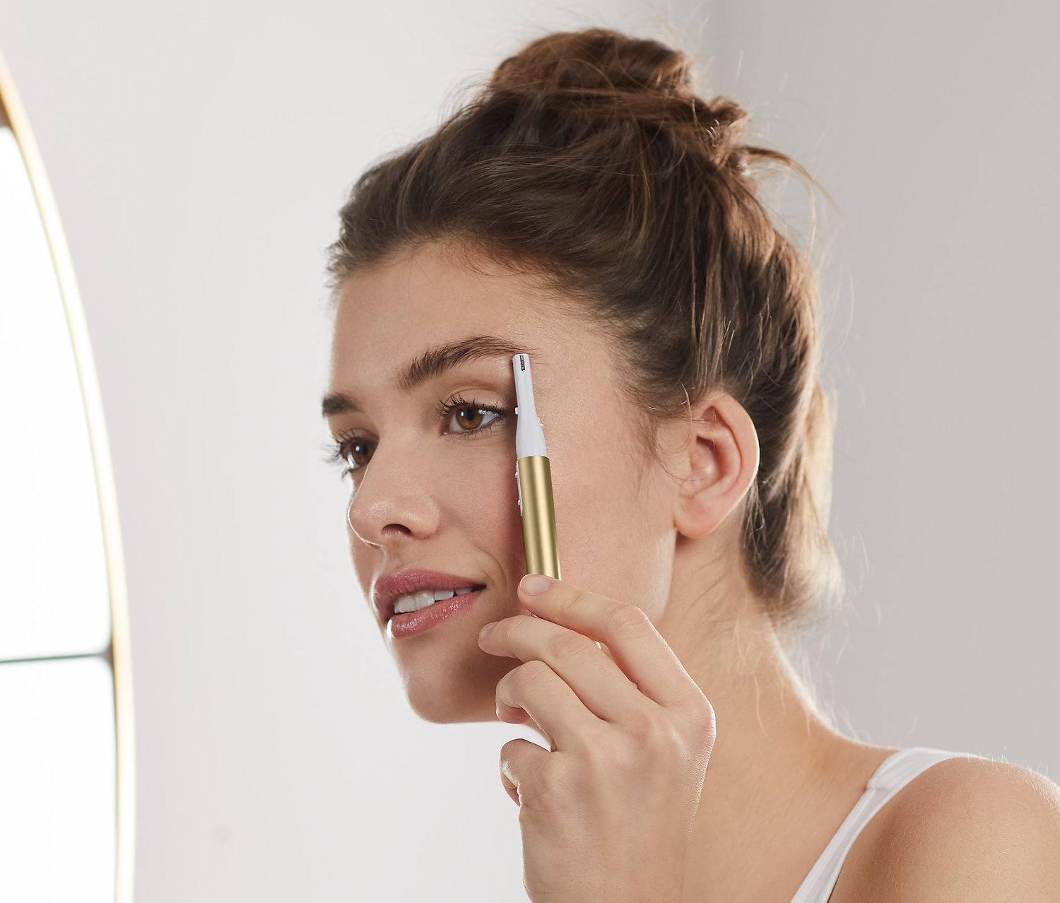 Kobieta przycina brwi elektrycznym trymerem do brwi.