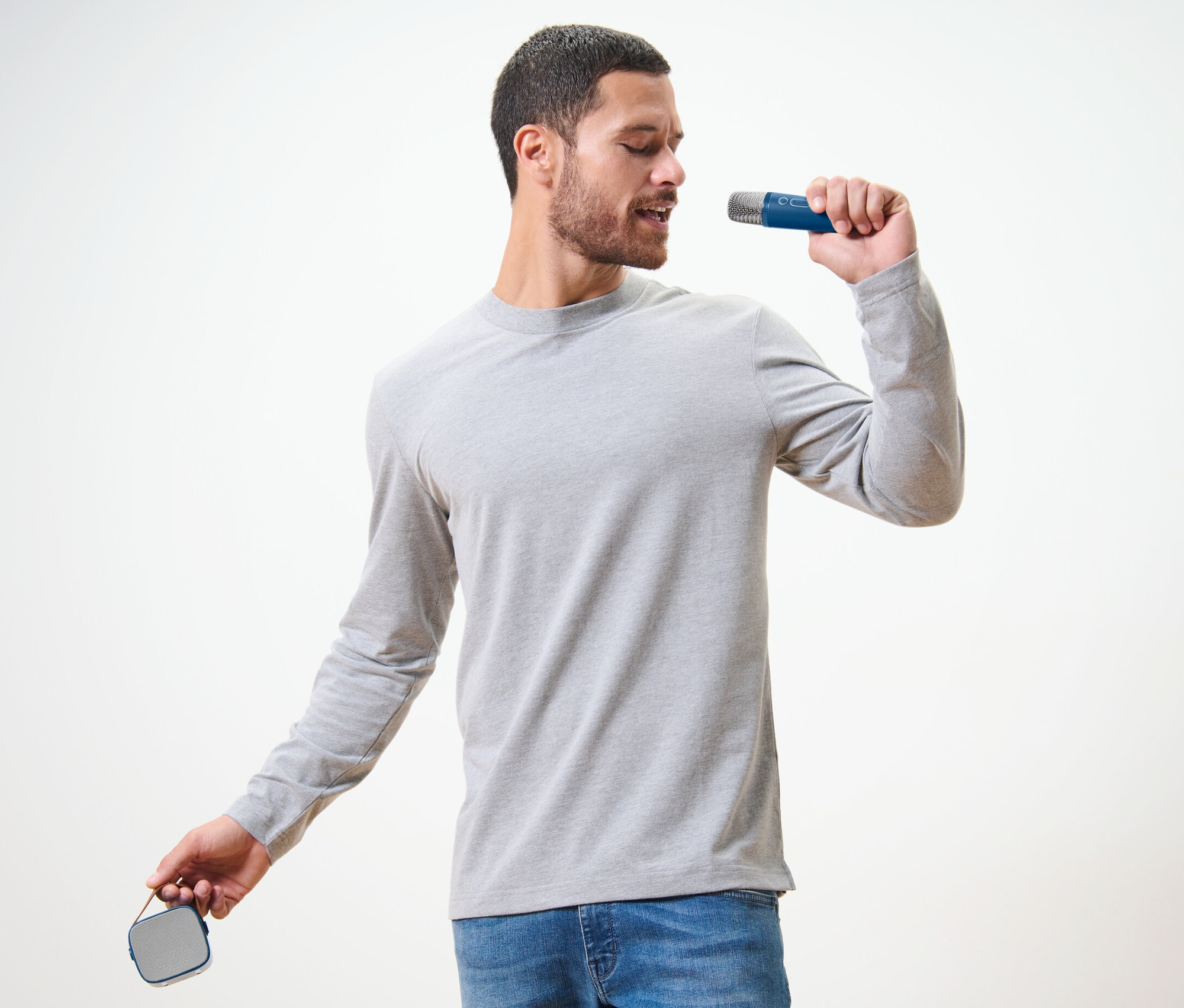 Mężczyzna śpiewa do mikrofonu z zestawu do karaoke z głośnikiem.