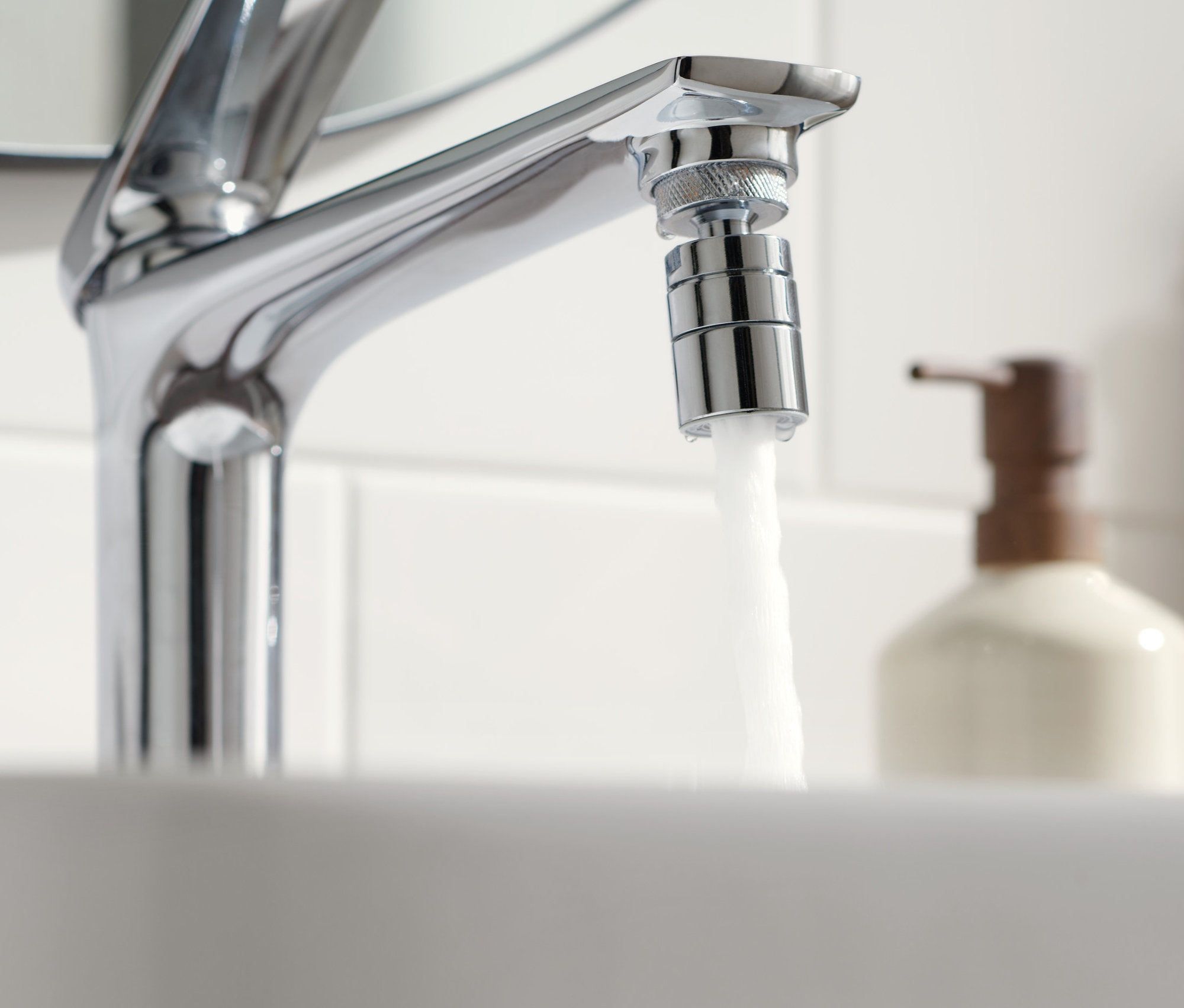 Woda leci z kranu z nasadką oszczędzającą wodę.