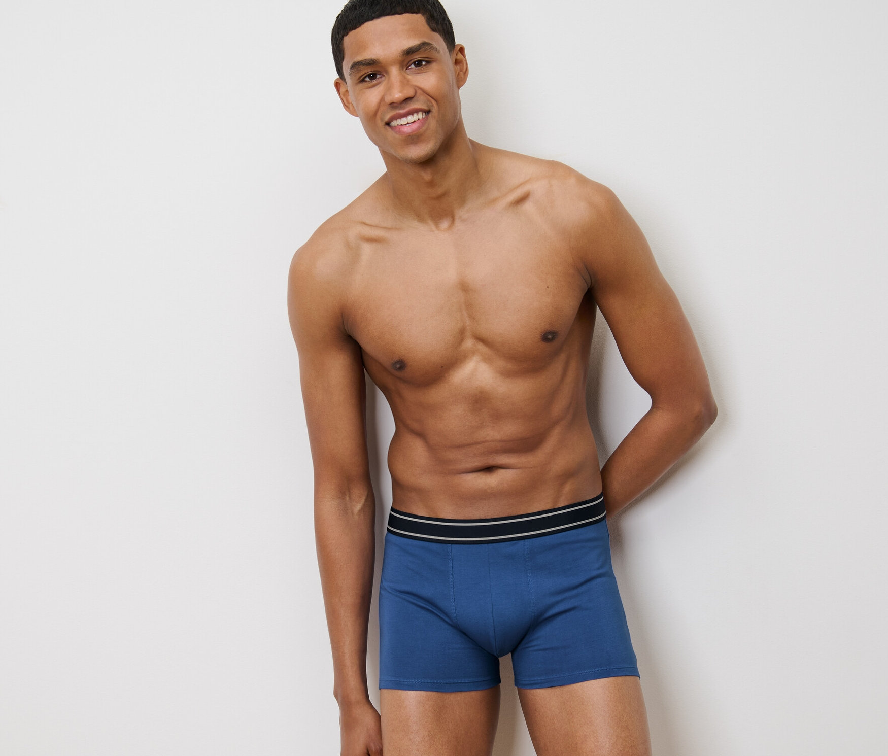 Uśmiechnięty mężczyzna pozuje w niebieskich bokserkach, 4 pary.