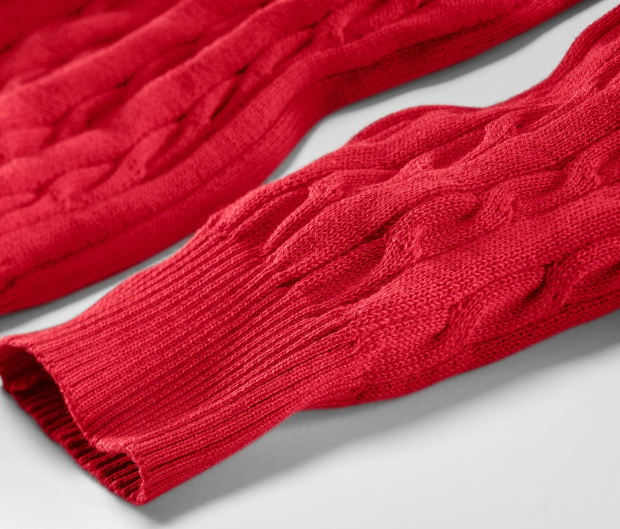 Zbliżenie na czerwony sweter z warkoczowym wzorem.