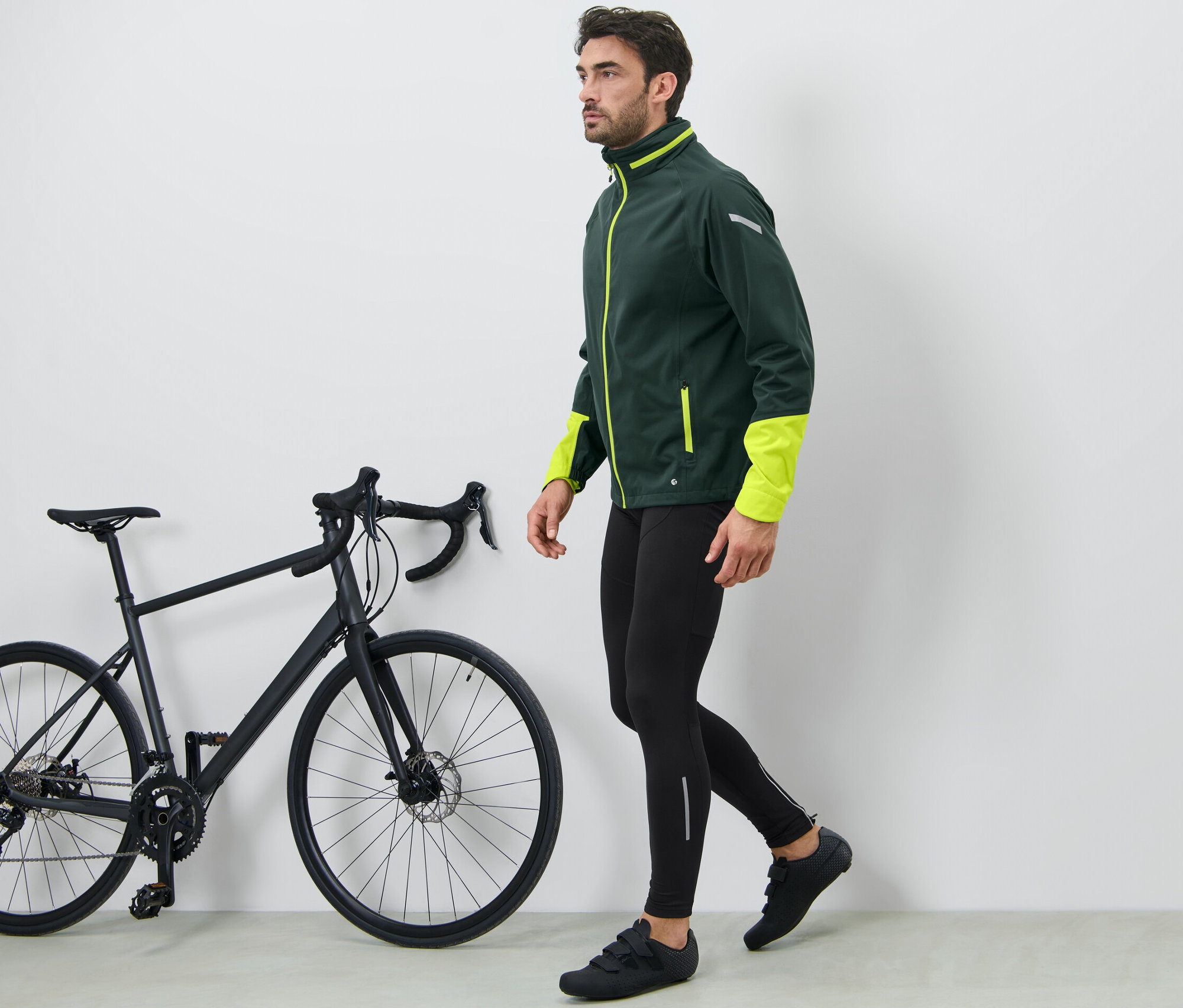 Mężczyzna idzie obok czarnego roweru i ma na sobie spodnie rowerowe.