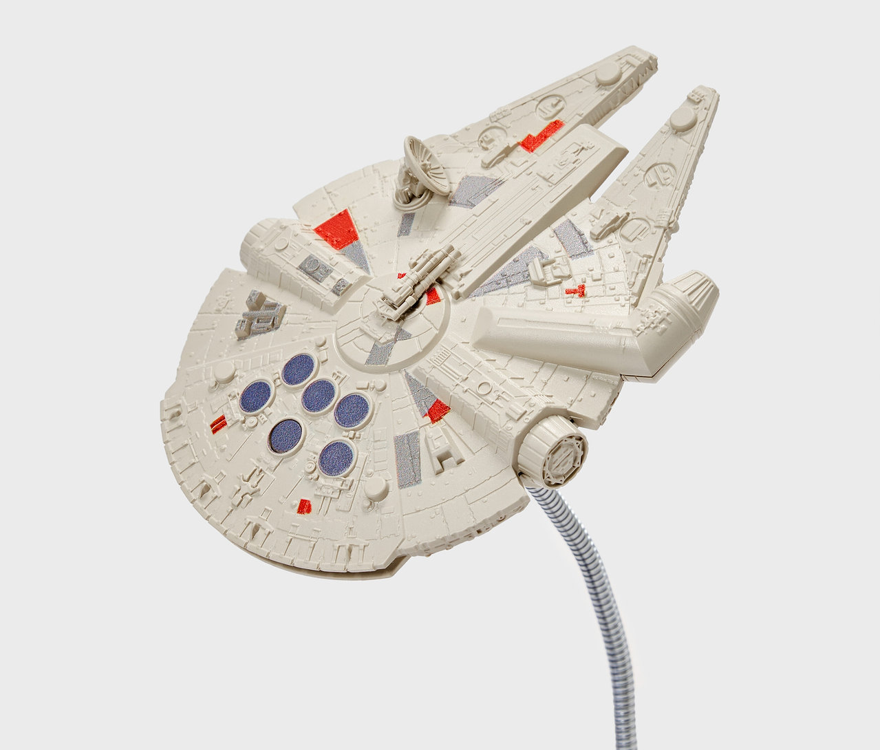Model statku Millennium Falcon z czerwonymi i szarymi detalami, przymocowany do elastycznego srebrnego trzpienia.