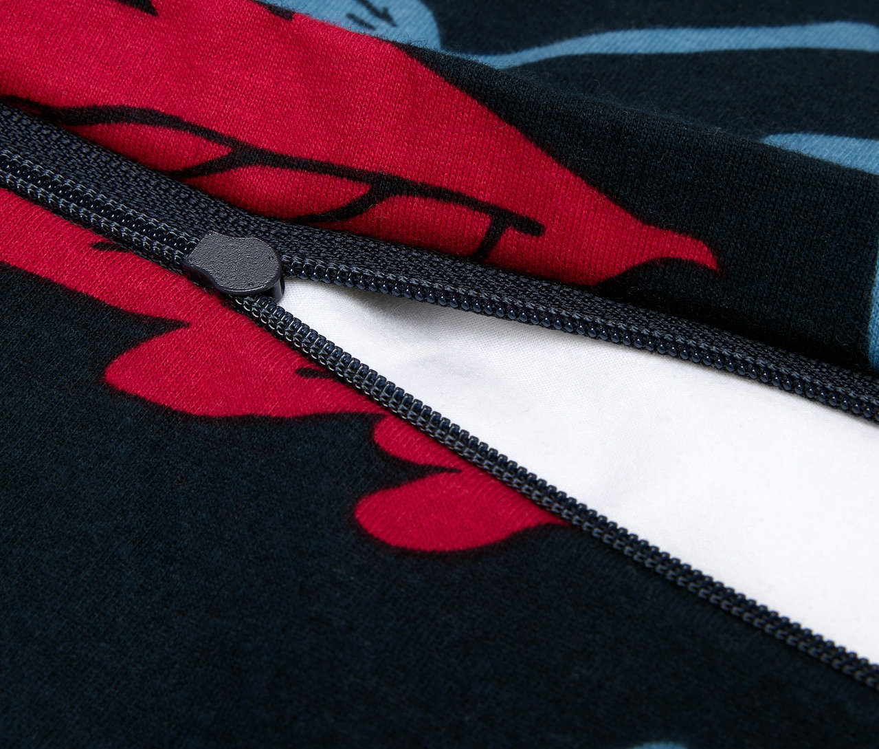 Zbliżenie na zamek błyskawiczny na granatowej poszwie na kołdrę z czerwonymi i niebieskimi kwiatami.