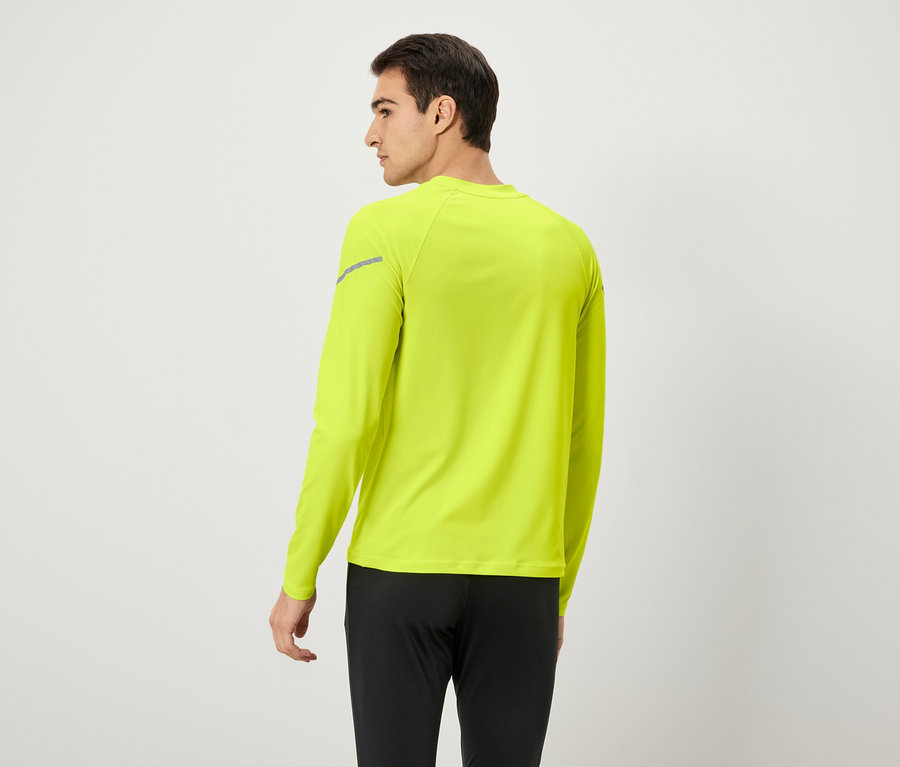 Mężczyzna tyłem, ubrany w neonowożółtą koszulkę z długim rękawem i czarne spodnie.