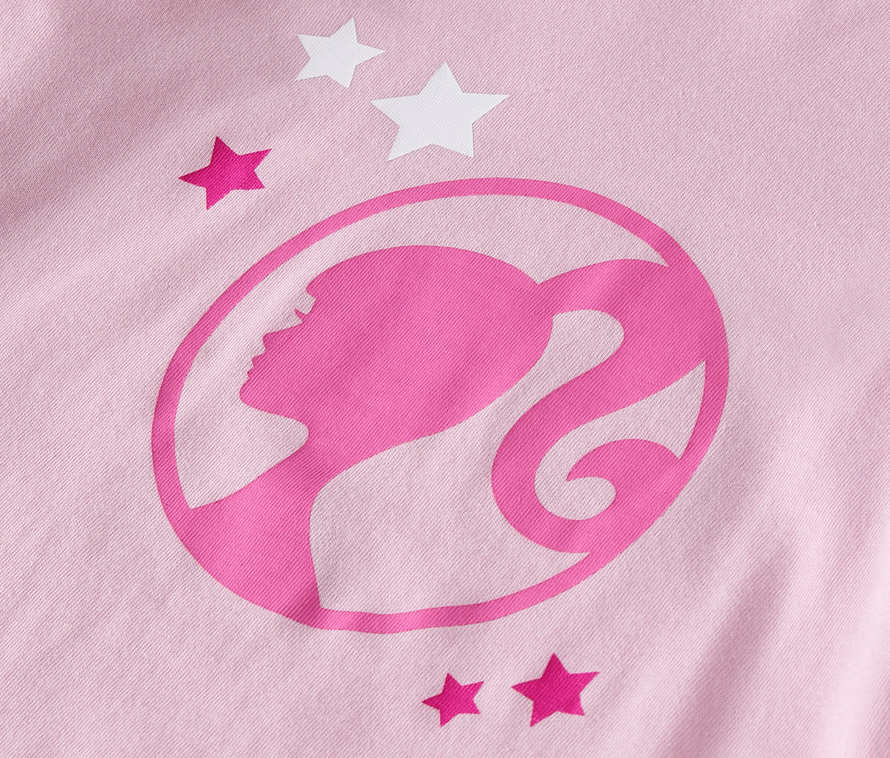 Zbliżenie na różową koszulkę z logo Barbie i gwiazdami.