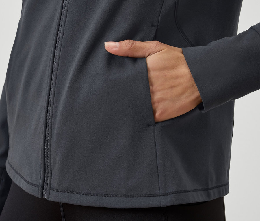 Szczegółowy widok szarej bluzy z zamkiem błyskawicznym, z ręką w kieszeni.