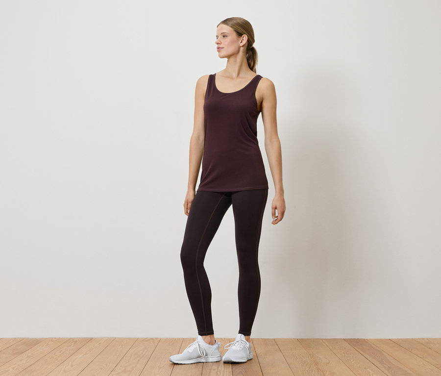 Kobieta w podkoszulku i legginsach pozuje w pomieszczeniu.