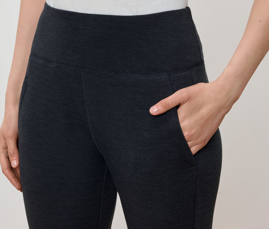 Kobieta trzyma rękę w kieszeni ciemnoszarych legginsów.