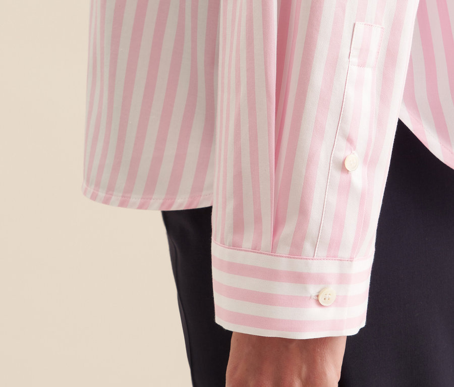 Zbliżenie na różową bluzkę koszulową oversize Seidensticker w białe paski na ramieniu kobiety.