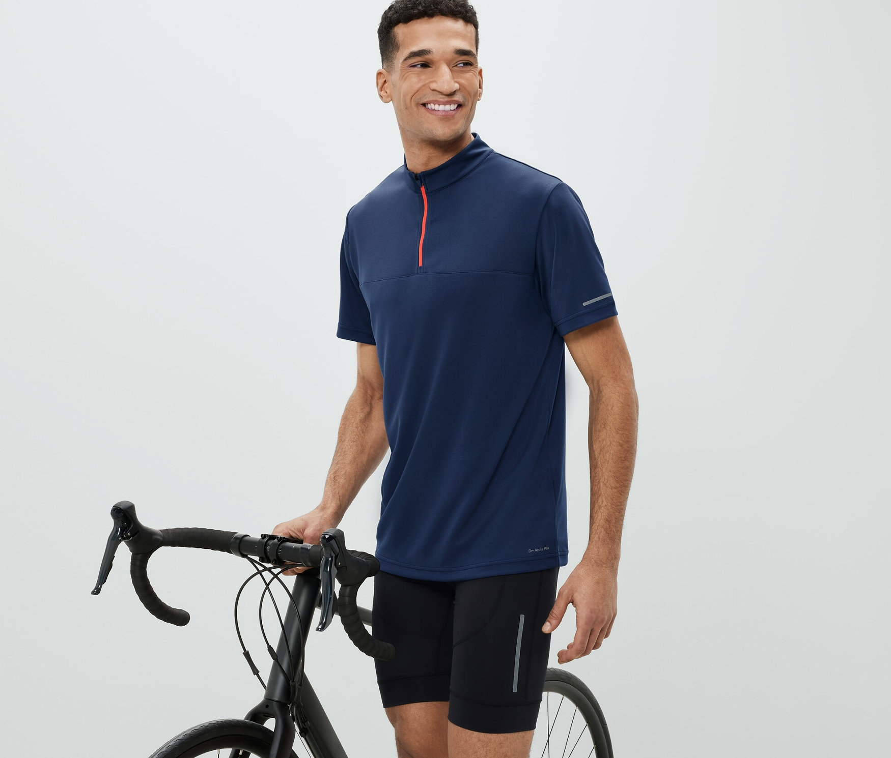 Mężczyzna obok roweru ma na sobie koszulkę rowerową.
