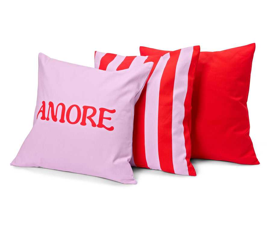 Trzy poduszki: liliowa z czerwonym napisem „AMORE”, w paski, czerwono-liliowa i jednolita czerwona.
