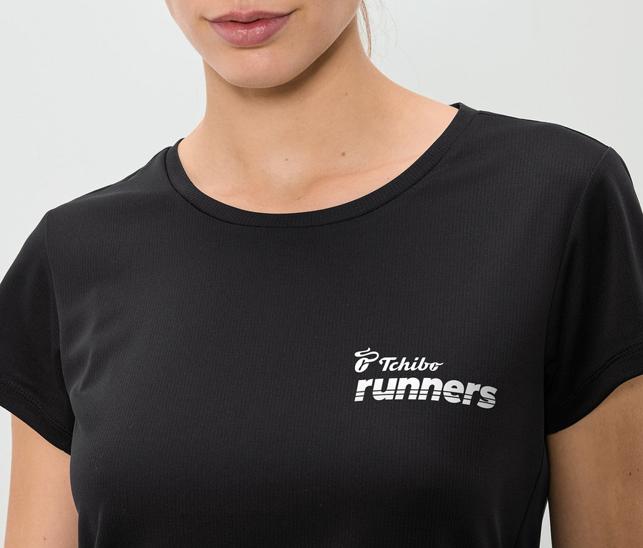 Zbliżenie kobiety w czarnej koszulce z napisem "Tchibo runners".