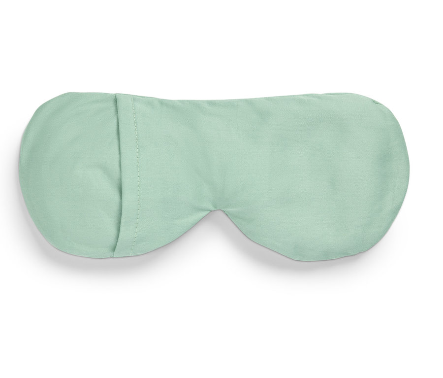 Jasnozielona maska do spania leży na białym tle.