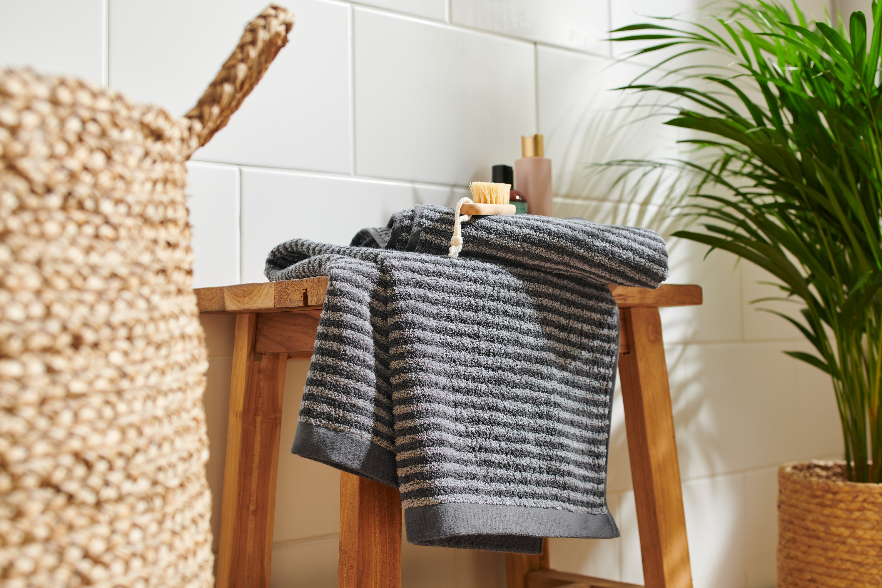 Na drewnianym stołku leżą dwa wysokiej jakości antracytowe ręczniki.