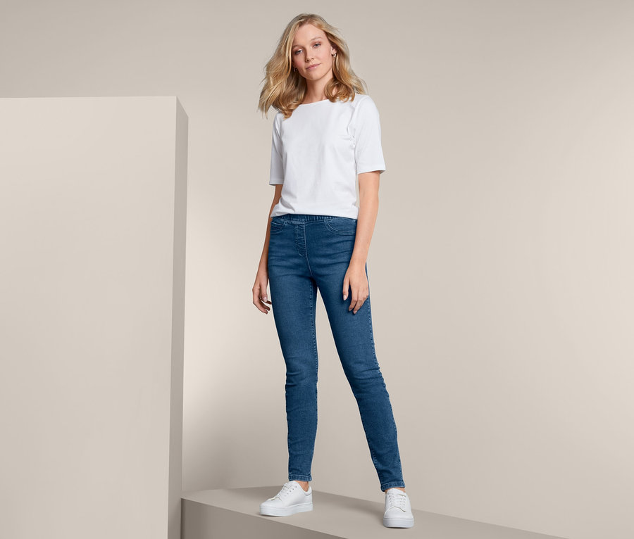 Blondynka pozuje w niebieskich tregginsach i białym T-shircie.