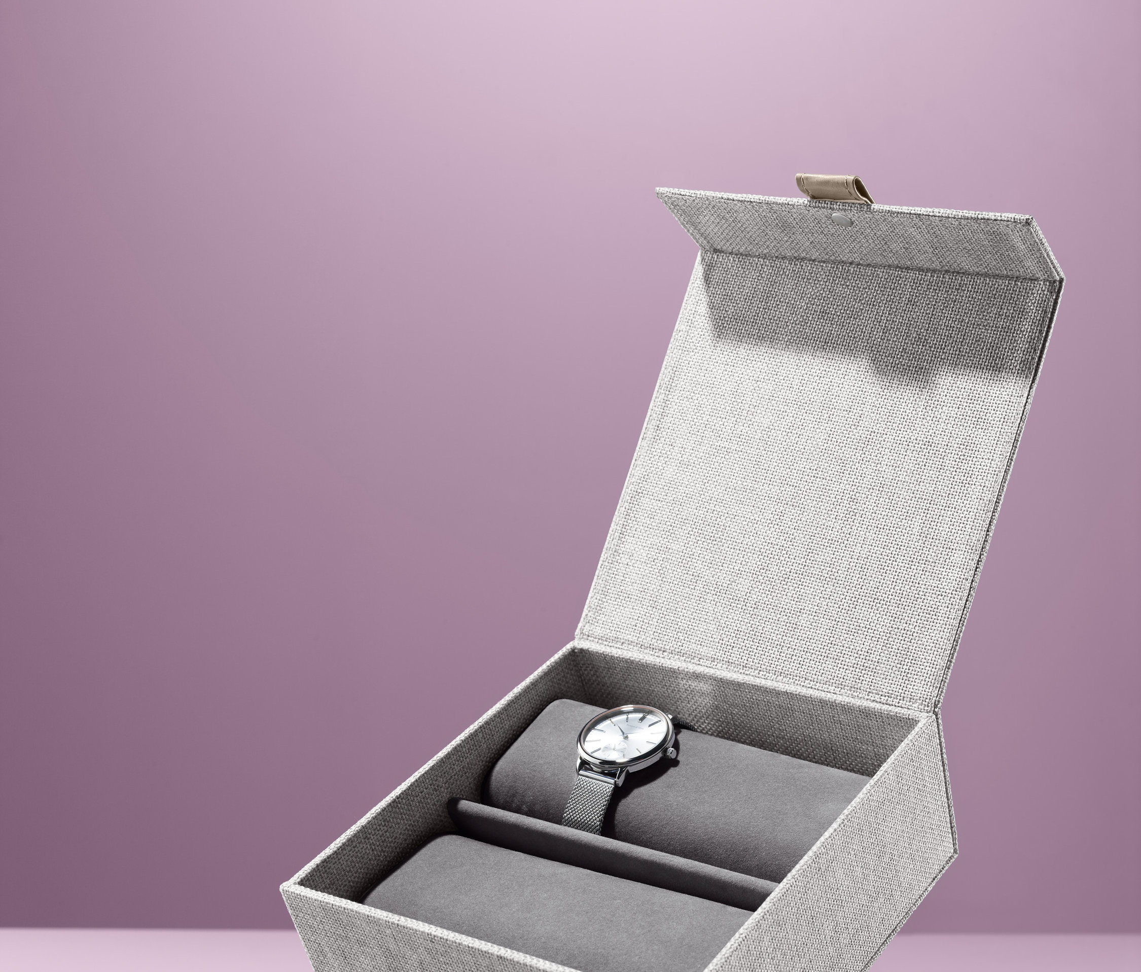 Otwarta kasetka na zegarki ze srebrnym zegarkiem w środku.