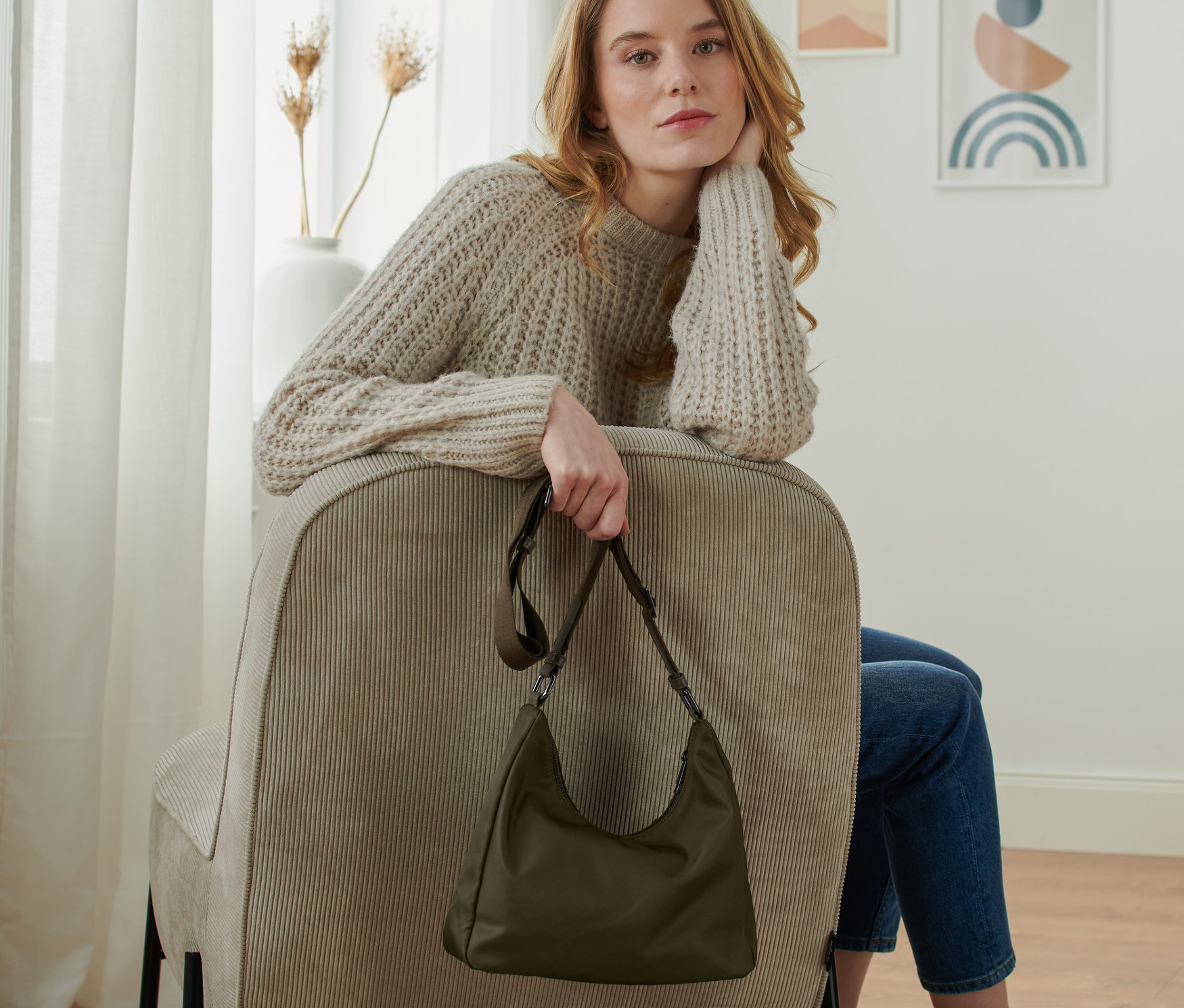 Kobieta siedzi na krześle i trzyma torbę na ramię.