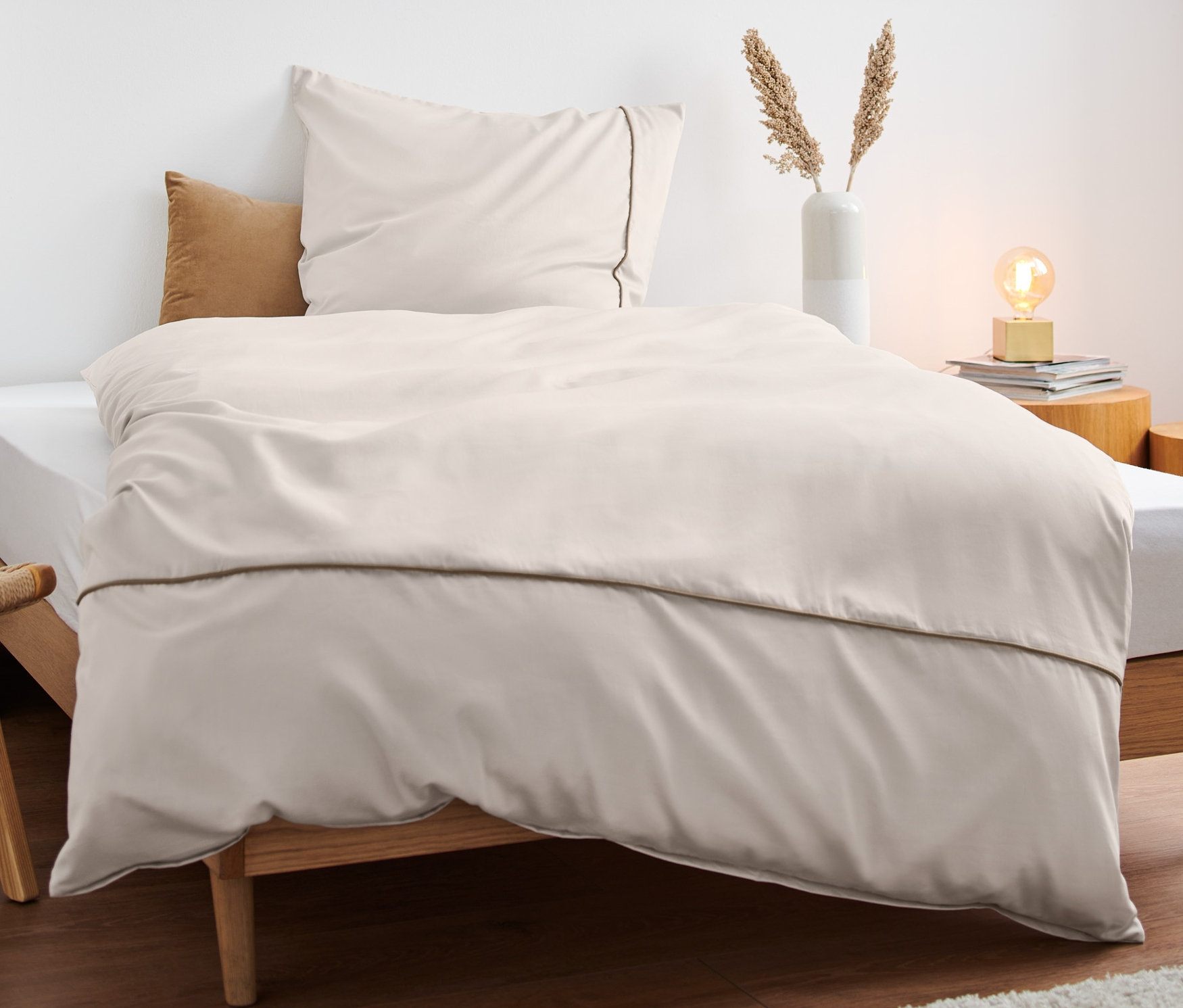 Beżowa pościel satynowa premium na łóżku z drewnianą ramą.