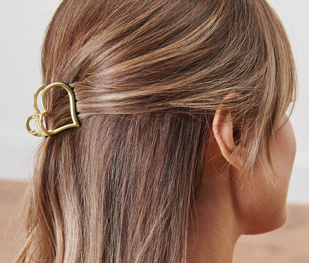 Widok z tyłu na kobietę z brązowymi włosami, które są spięte spinką do włosów w kształcie serca.