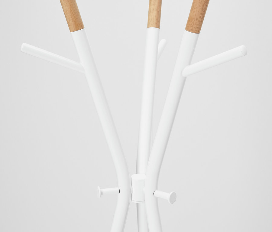 Detal białego wieszaka na ubrania z drewnianymi elementami.