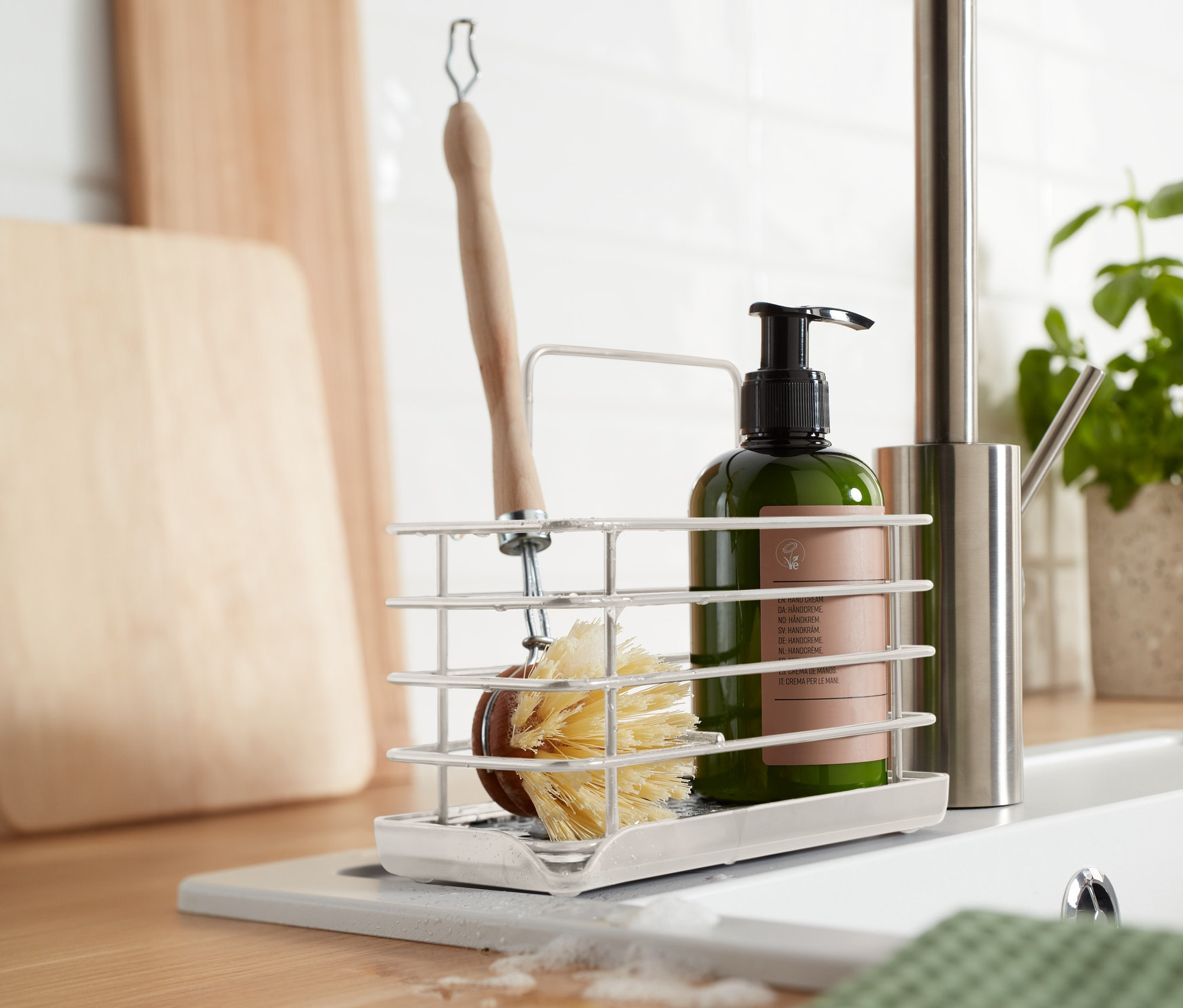 W kuchni znajduje się metalowy stojak na przybory do zmywania z szczotką i butelką mydła.